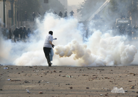 DEMONSTRATOR PREPARES TO THROW TEAR GAS CANISTER BACK AT POLICE IN CAIRO
