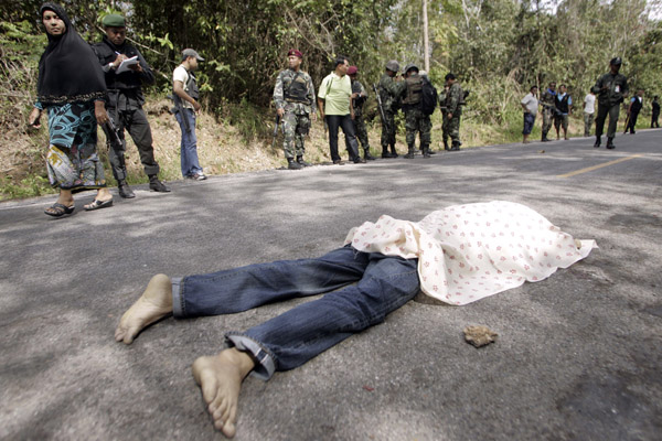 ATTENTION EDITORS - VISUALS COVERAGE OF SCENES OF DEATH AND INJURY A dead body of a villager lies on the ground as Thai security personnel inspect the site at an attack in the southern Pattani province January 24, 2011. Insurgent shot a Muslim villager in an another attack in Thailand's restive deep south, police said. REUTERS/Surapan Boonthanom (THAILAND - Tags: POLITICS CIVIL UNREST) TEMPLATE OUT