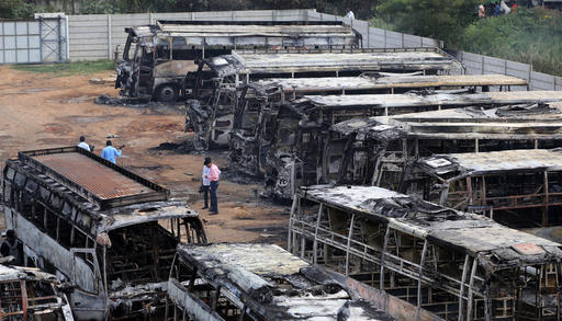 Charred remains of passenger buses, owned by a transport company from the neighboring Tamil Nadu state, lie in a yard a day after they were set ablaze by angry mobs, in Bangalore, in the southern Indian state of Karnataka, Tuesday, Sept. 13, 2016. Incidents of looting and vandalism eased Tuesday in parts of India's information technology hub of Bangalore after authorities imposed a curfew amid widespread protests overnight over India's top court ordering the southern state of Karnataka to release water from a disputed river to Tamil Nadu. (AP Photo/Aijaz Rahi)